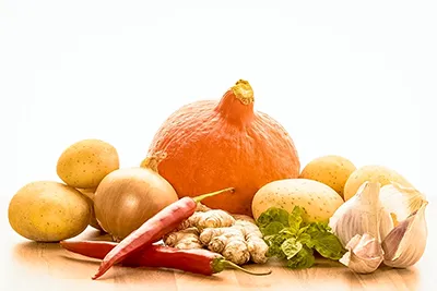 Appetitliche Food-Fotografie: Stillleben mit frischem Gemüse. Visuelle Inszenierung für Lebensmittel und Gastronomie. Farbenfrohes Stillleben mit frischem Gemüse: Kürbis, Kartoffeln, Zwiebel, Chili, Ingwer, Knoblauch und Minze. Ausdrucksstarke Food-Fotografie.